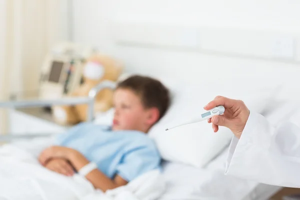 Doctor holding thermometer with boy in hospital — Stock Photo, Image