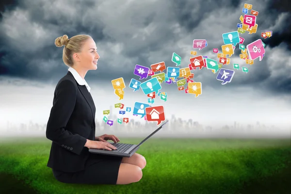 Businesswoman using laptop with app icons — Stock Photo, Image