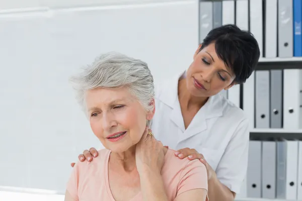 Chiropratico guardando la donna anziana con dolore al collo — Foto Stock