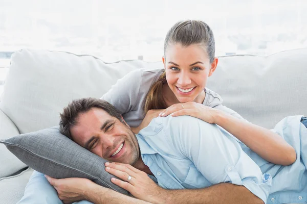 幸福的夫妇，他们在照相机微笑的沙发上放松 — 图库照片