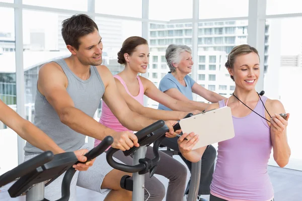 Trainer besides people working out at spinning class — Stock Photo, Image
