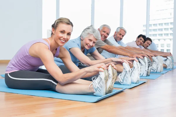 Classe allungamento delle mani alle gambe a lezione di yoga — Foto Stock
