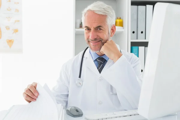 Mature male doctor with computer at medical office — Stock Photo, Image