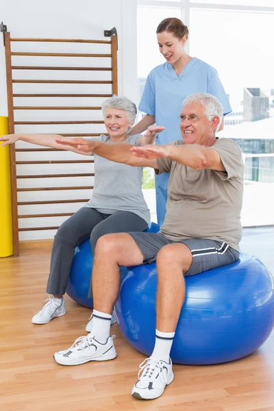 Therapist assisting senior couple with exercises — Stock Photo, Image