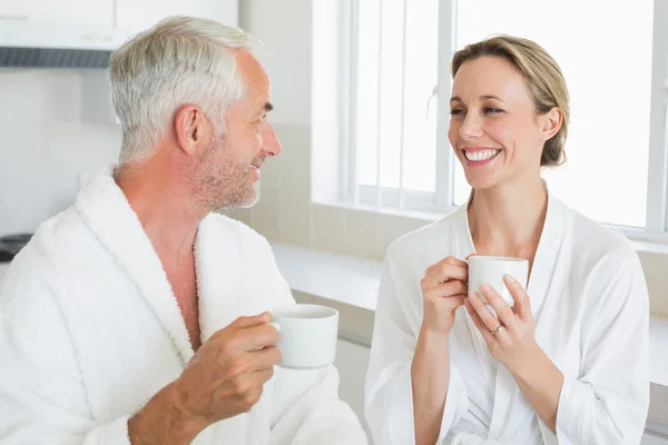 Smiling couple having coffee at breakfast in bathrobes — Stock Photo, Image