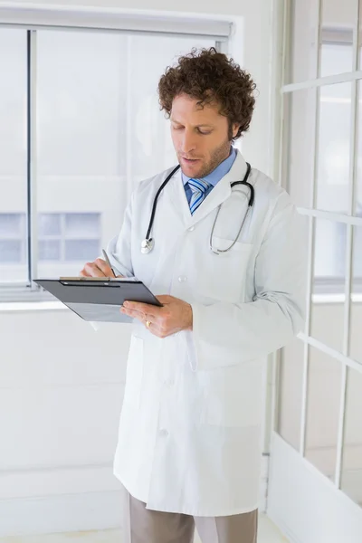 Male doctor writing reports in hospital — Stock Photo, Image