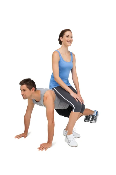 Kobieta trener siedzi na człowieka jak on push up — Zdjęcie stockowe