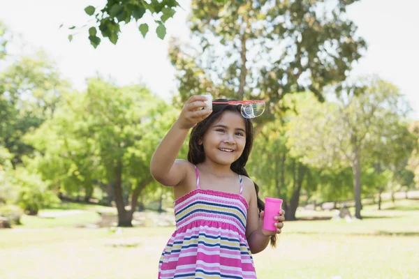 Cheerful girl blowing soap bubbles at park — Stock Photo, Image