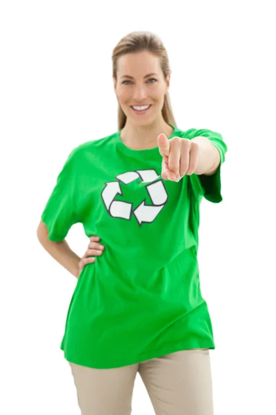 Улыбающаяся женщина в футболке с символом вторичной переработки, указывающая на камеру — стоковое фото