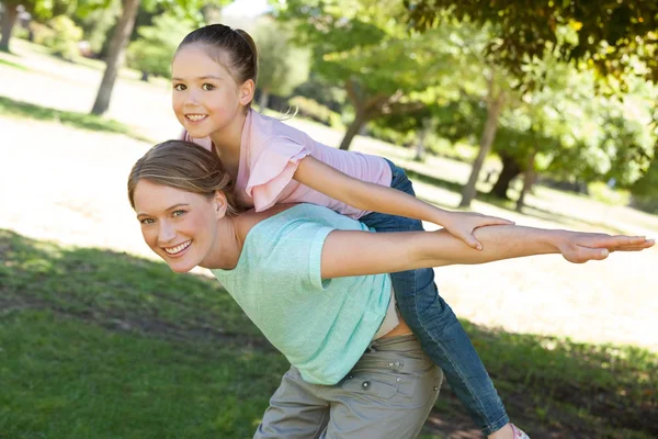 Mãe feliz carregando filha no parque — Fotografia de Stock