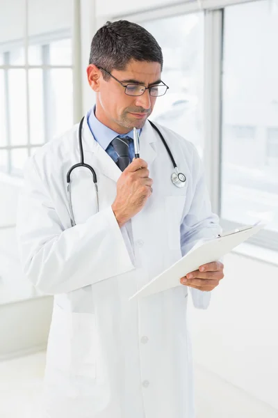 Male doctor reading reports in hospital — Stock Photo, Image