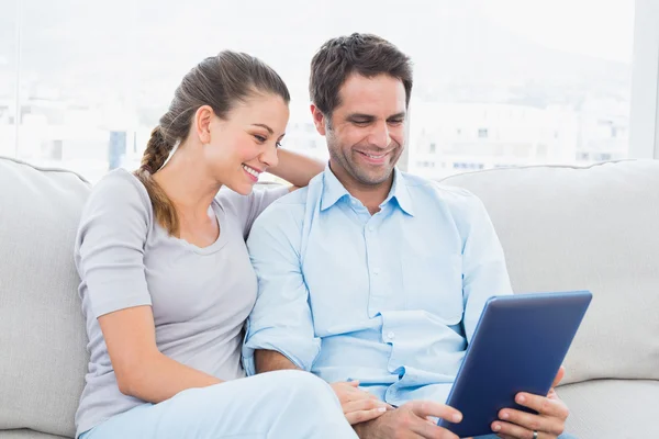 Couple souriant assis sur le canapé en utilisant la tablette pc — Photo