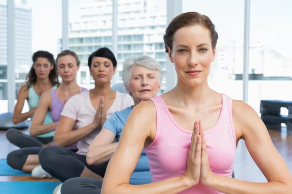 Klassen sitter med sammanfogade händer i rad på yogaklass — Stockfoto