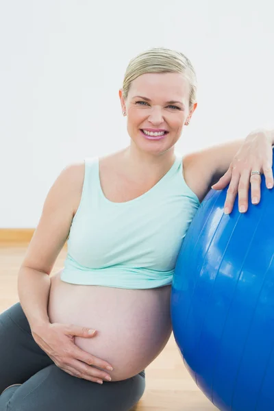 Happy pregnant woman leaning against exercise ball holding her b — Stock Photo, Image