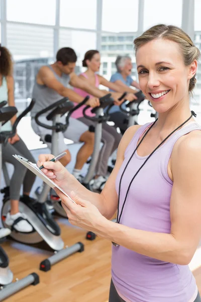 Entrenador con gente haciendo ejercicio en la clase de spinning —  Fotos de Stock