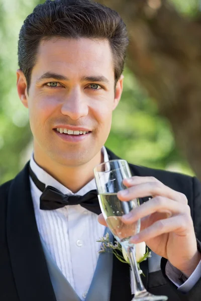 Groom drinking champagne in garden — Stock Photo, Image