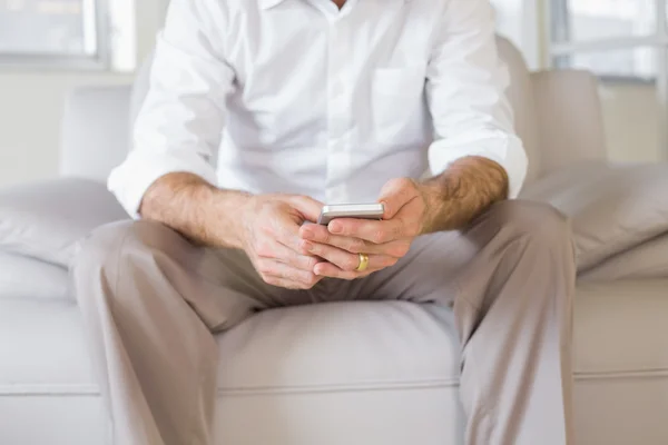 Mittlerer Abschnitt eines gut gekleideten Mannes Textnachrichten zu Hause — Stockfoto