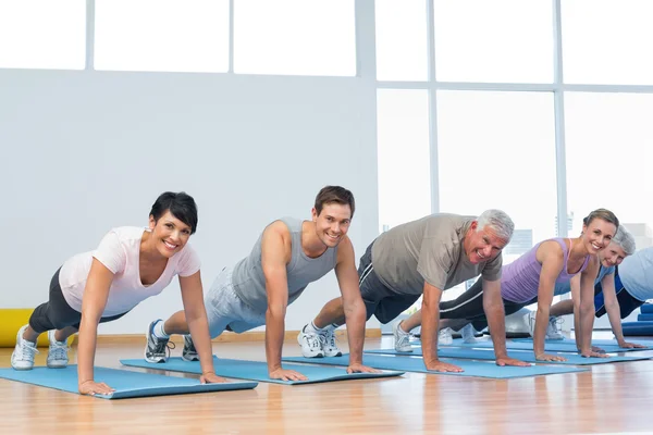 Groep doet push ups in rij op yoga klas — Stockfoto