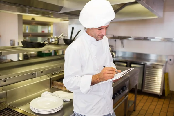 Cocinero escribiendo en el portapapeles en la cocina —  Fotos de Stock