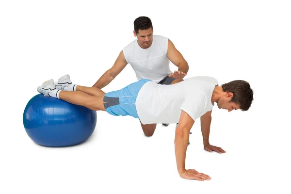 Trainer helpen jonge man oefening op fitness bal — Stockfoto