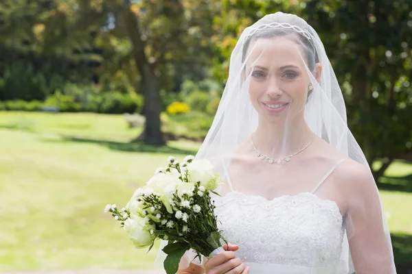 Novia sonriendo a través del velo en el jardín — Foto de Stock