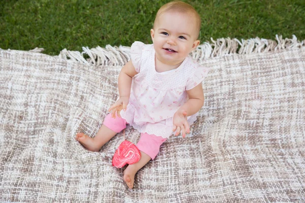 Cute baby with heart shaped lollipop sitting on blanket at park — Stock Photo, Image