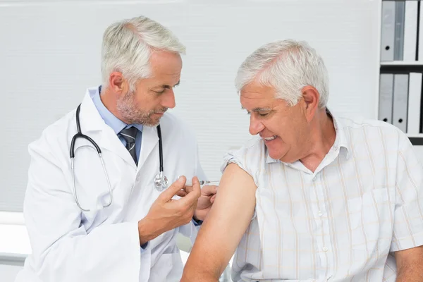 Médico injetando paciente idoso do sexo masculino — Fotografia de Stock