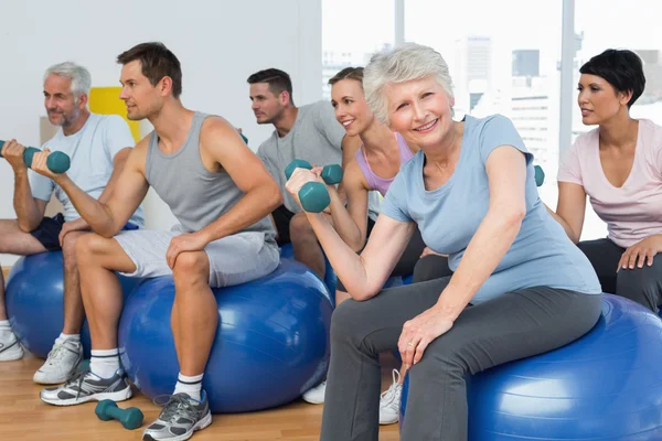 Lezione di fitness con manubri seduti su palline in palestra — Foto Stock