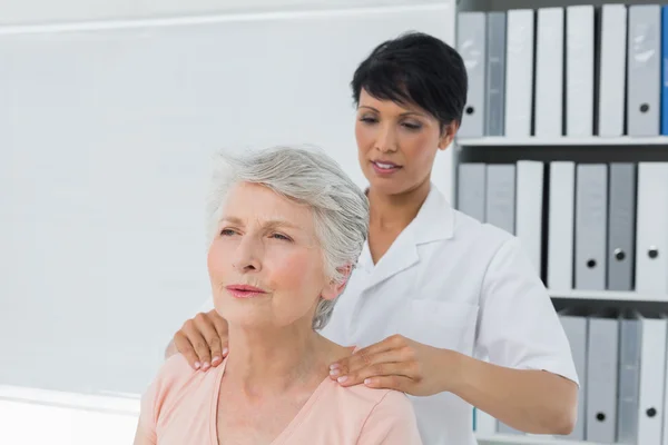 Chiropractor massaging a senior womans shoulder — Stock Photo, Image