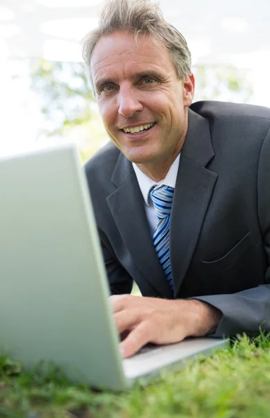 Homem de negócios usando laptop no parque — Fotografia de Stock