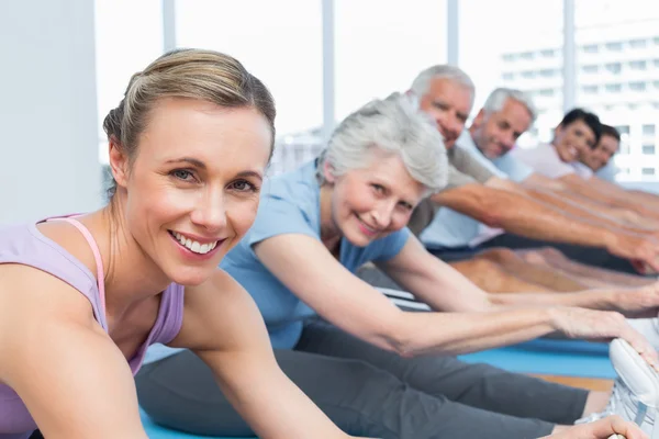 Class stretching hands to legs at yoga class — Stock Photo, Image