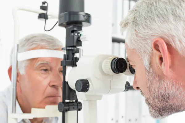 Optométriste effectuant des tests à vue pour un patient âgé — Photo