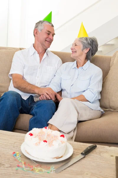Seniorenpaar sitzt auf Couch und feiert Geburtstag — Stockfoto