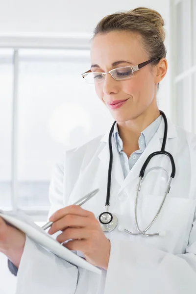 Beautiful female doctor with clipboard in hospital — Stock Photo, Image