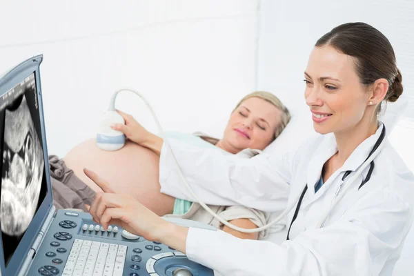 Médico mostrando mujer su bebé en ultrasonido —  Fotos de Stock