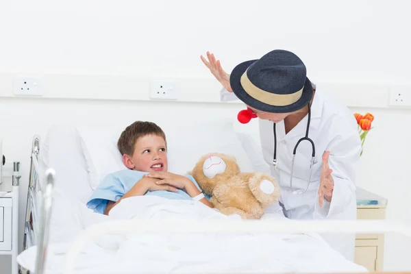 Doutor divertido menino doente na cama do hospital — Fotografia de Stock