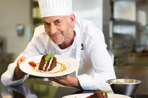 Pasticcere maschio sorridente con dolce in cucina — Foto Stock