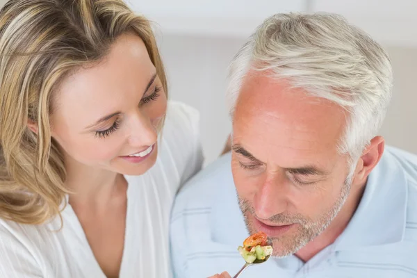 Femme heureuse nourrissant son partenaire d'une cuillère de légumes — Photo