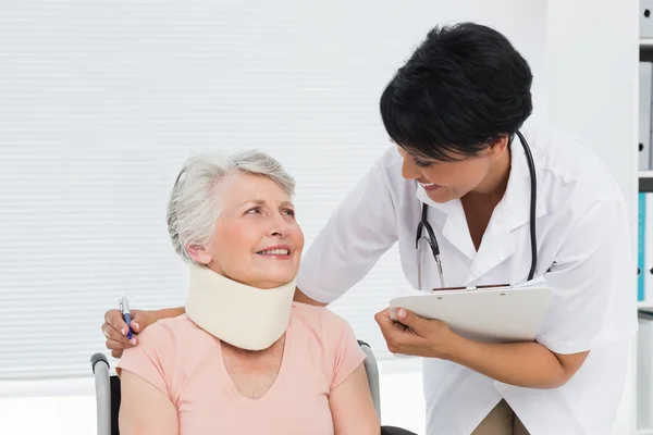 Läkare pratar med en äldre patient med cervikalkragen — Stockfoto