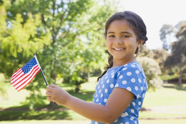 Chica sosteniendo la bandera americana en el parque — Foto de Stock