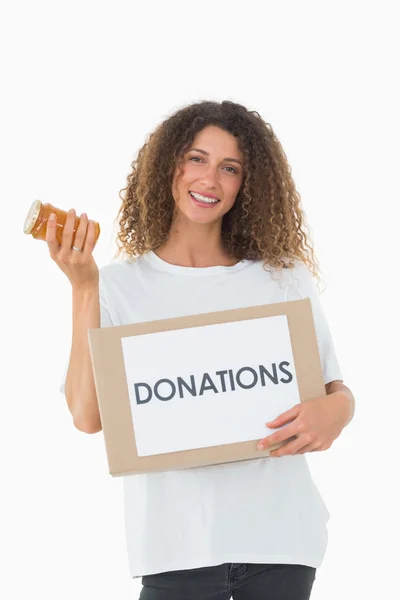 Happy volunteer holding a box of donations and jam jar — Stock Photo, Image