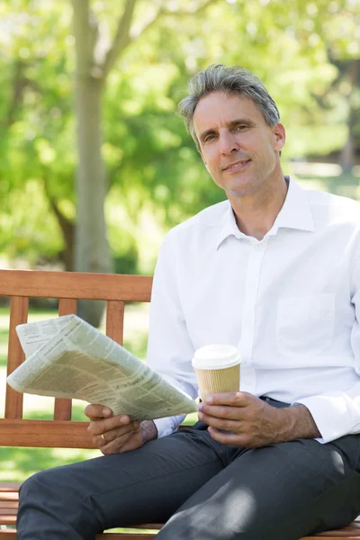 Uomo d'affari con tazza e giornale nel parco — Foto Stock