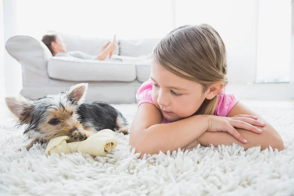 Kleines Mädchen auf Teppich liegend mit Yorkshire Terrier — Stockfoto