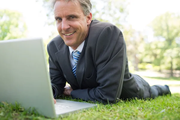 Empresário com laptop deitado no parque — Fotografia de Stock