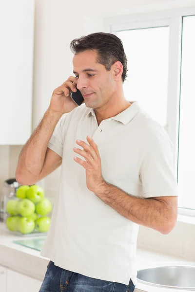 Uomo che utilizza il telefono cellulare in cucina — Foto Stock