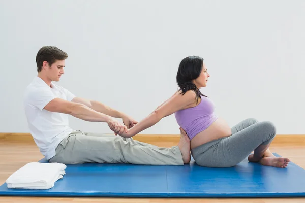 Masseur étirant les femmes enceintes bras et épaules sur un tapis — Photo