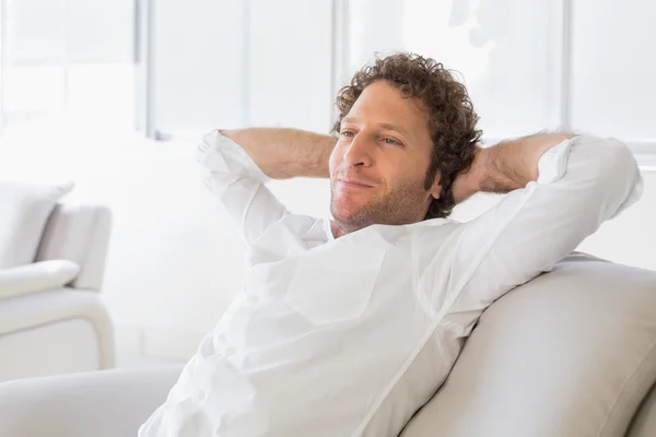 Relaxed man sitting with hands behind head at home — Stock Photo, Image