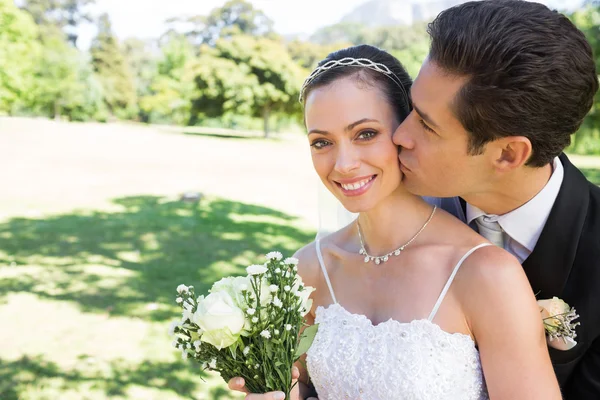 Groom kissing bride on cheek in garden — Stock Photo, Image