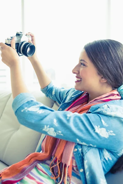 Brünette sitzt auf Sofa und macht ein Selfie — Stockfoto