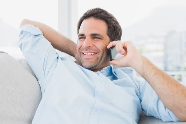 Szczęśliwy człowiek siedzi na kanapie w telefonie — Zdjęcie stockowe